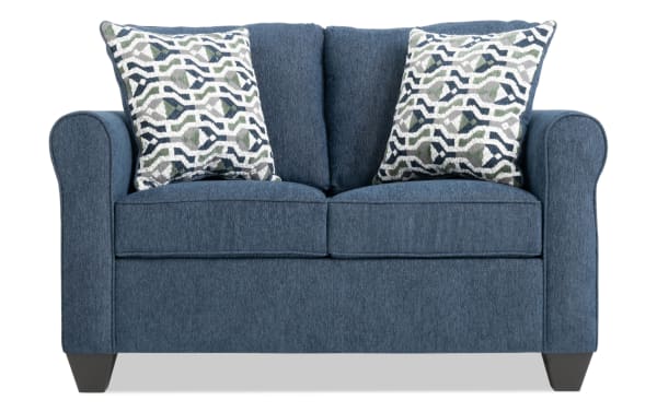 Slumber Navy 56'' transitional sleeper sofa in blue polyester fabric with rolled arms, plush cushions, and two patterned accent pillows.