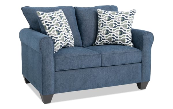 Slumber Navy 56" transitional sleeper sofa in blue polyester fabric with plush cushions, patterned accent pillows, and a twin gel memory foam mattress.