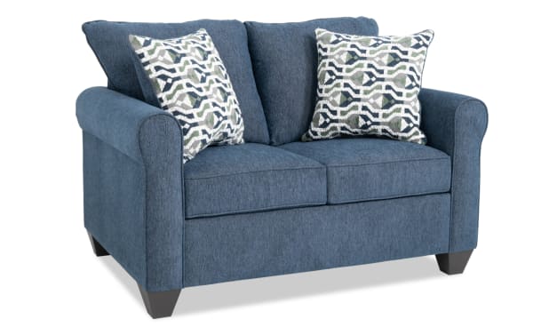 Slumber Navy 56'' transitional sleeper sofa in blue polyester fabric with plush cushions, patterned accent pillows, and a cooling twin pull-out mattress.