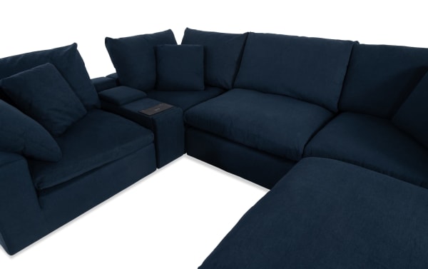 Dream Navy 131'' 6-piece modular sectional in navy blue polyester fabric, transitional style with 3 corners, armless chair, console with USB/USB-C ports, and ottoman. Features oversized reversible cushions with jersey knit-like fabric and feather blend topper for customizable living room seating.