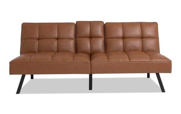 Dallas Cognac Futon in transitional style with brown faux leather upholstery, tufted seat and back cushions, and angled black metal legs.