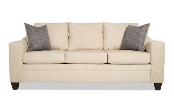 Claudia 84" beige transitional sofa upholstered in polyester fabric, featuring three seat cushions and two gray accent pillows for added comfort.
