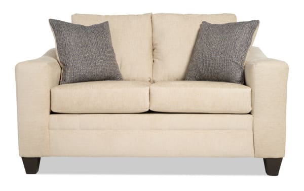 Claudia 62'' beige loveseat in transitional style with soft polyester fabric upholstery, featuring two textured gray accent pillows and sturdy dark wood legs.