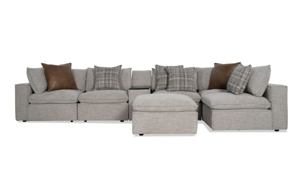Infinity Gray 117'' 7-piece modular sectional in gray polyester fabric, transitional style with 3 armless chairs, 2 corners, media console, ottoman, feather-blend pillows, Bluetooth speakers, and removable cushions.