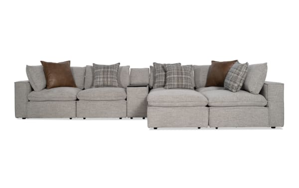 Gray Infinity 7-piece modular sectional sofa with 3 armless chairs, 2 corners, media console, and ottoman. Polyester fabric upholstery in transitional style with plush cushions and mixed plaid and brown accent pillows.