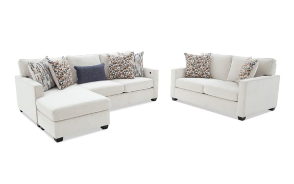 Beige fabric sectional sofa with chaise lounge and matching loveseat, featuring decorative patterned and navy blue throw pillows, modern design.