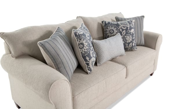 Beige Portland 85'' transitional sleeper sofa upholstered in soft polyester fabric, featuring rolled arms and multiple patterned accent pillows.