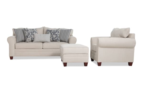 Portland Beige 85'' transitional sofa, chair, and storage ottoman set in soft beige polyester fabric with accent pillows for comfortable living room seating.