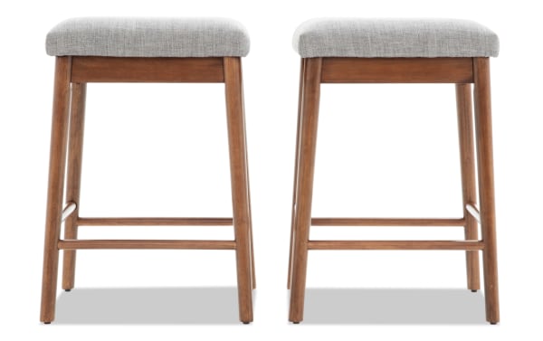 Two mid-century modern wooden bar stools with light gray upholstered cushioned seats, tapered legs, and footrests, ideal for kitchen or bar seating.