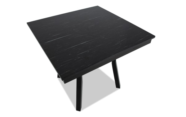 Square black wooden table with a textured surface and angled legs, suitable for modern dining or office use.