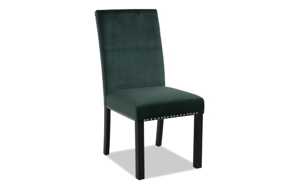 Dark green velvet dining chair with silver nailhead trim and black wooden legs, featuring a padded seat and high backrest for comfort.