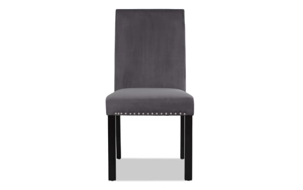 Modern dining chair with dark gray velvet upholstery, silver nailhead trim, and black wooden legs, ideal for contemporary interiors.