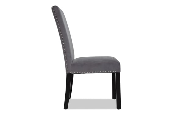 Gray upholstered dining chair with nailhead trim along the backrest and seat edges, featuring black wooden legs and a cushioned seat.