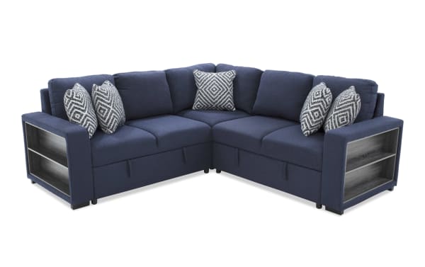 Blue fabric sectional sofa with built-in gray wood storage shelves on the armrest, featuring patterned throw pillows and modern design.