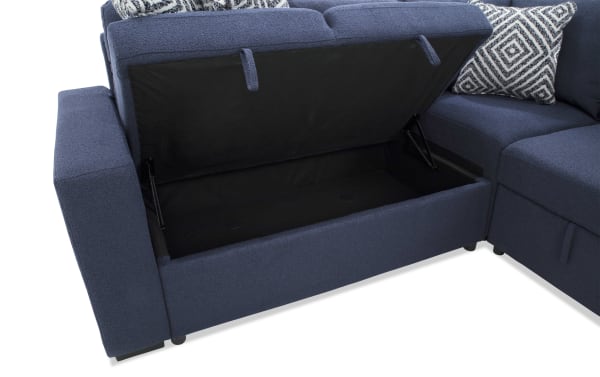 Blue fabric sectional sofa with storage compartment under the seat, featuring black interior lining and patterned throw pillows.
