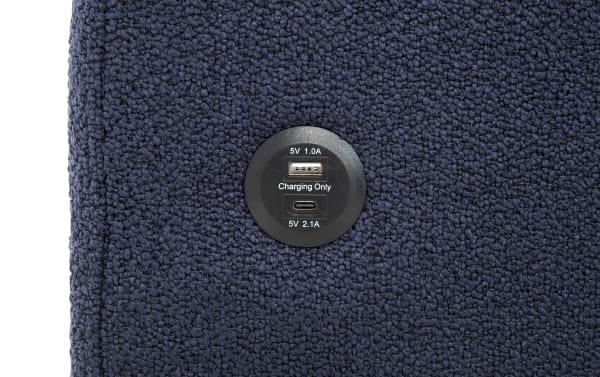 Circular black USB charging port on dark blue textured fabric, featuring one USB-A port labeled "5V 1.0A Charging Only" and one USB-C port labeled "5V 2.1A" for device charging.
