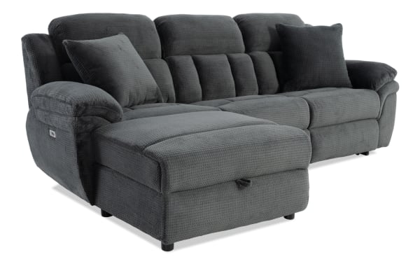 Dark gray sectional sofa with plush textured fabric, padded armrests, and two matching cushions, designed for living room comfort and style.