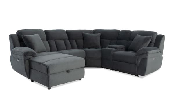 Dark gray sectional sofa with plush fabric upholstery, padded armrests, multiple cushions, and a chaise lounge on the left side.