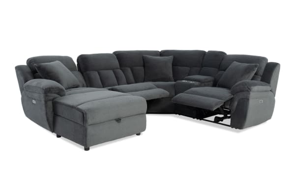 Dark gray fabric sectional sofa with plush cushions, reclining seats, and an ottoman, designed for comfort and modern living rooms.