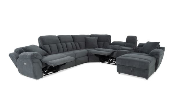 Dark gray fabric sectional sofa with plush cushions, reclining seats, and an ottoman, designed for comfort and modern living rooms.