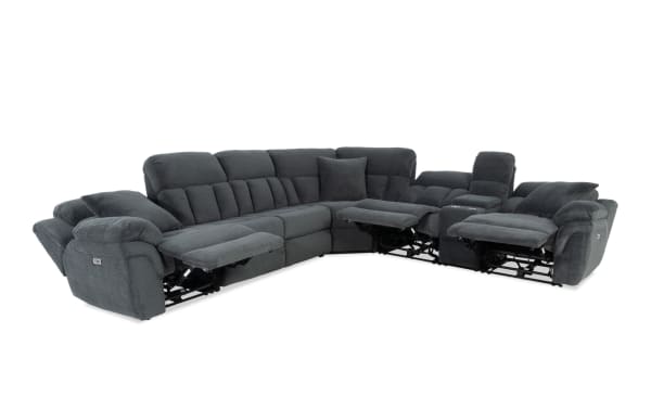 Dark gray fabric sectional sofa with plush cushioning and three recliners extended, featuring padded armrests and a corner design for spacious seating.