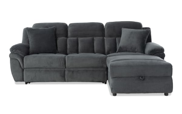 Dark gray sectional sofa with plush fabric upholstery, padded armrests, cushioned backrests, and two matching throw pillows, ideal for modern living rooms.
