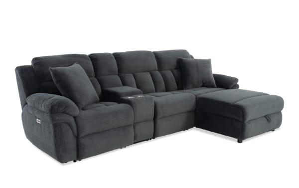 Dark gray fabric sectional sofa with plush cushioning, two matching pillows, built-in cup holders, and a chaise lounge on the right side.