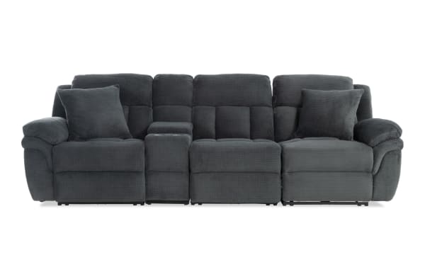 Dark gray fabric reclining sectional sofa with plush cushions, padded armrests, two matching throw pillows, and a center console with cup holders.