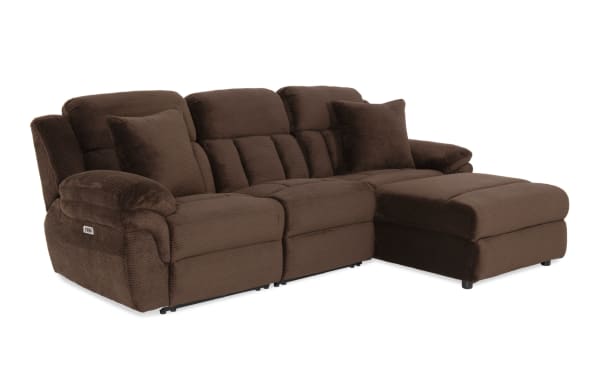 Brown plush fabric sectional sofa with reclining seats, cushioned armrests, and two matching throw pillows, designed for living room comfort.