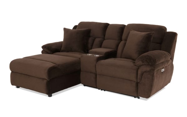 Brown sectional reclining sofa with plush corduroy fabric, two matching throw pillows, cup holders, and padded armrests for living room comfort.