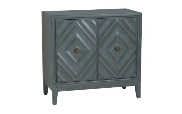 Blue-gray wooden cabinet with two doors featuring diamond-patterned paneling and round brass knobs, standing on four legs.