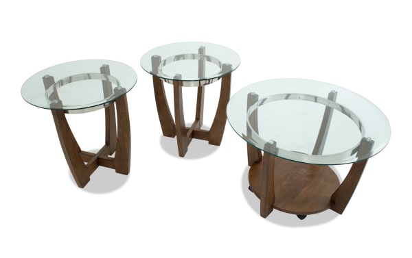 Set of three modern glass-top tables with round clear tempered glass surfaces and dark wood curved legs, ideal for living room decor.