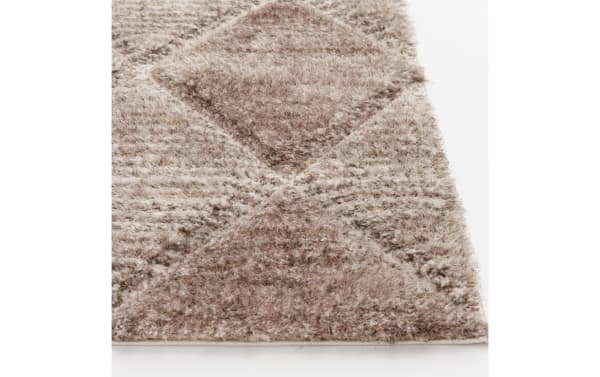 Close-up of a beige and brown textured shaggy rug with a geometric diamond pattern, showcasing its soft, plush fibers and detailed weave.
