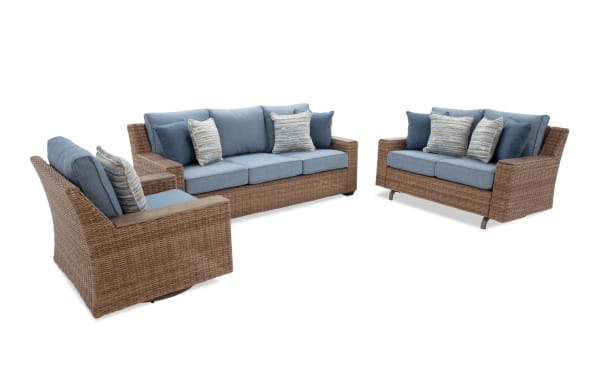 Outdoor wicker patio furniture set with blue cushions, including a three-seat sofa, loveseat, and armchair, featuring woven rattan frames and decorative pillows.