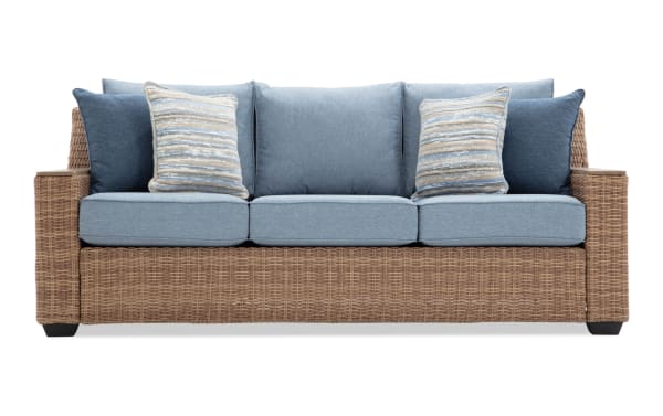Three-seater wicker sofa with light blue cushions and patterned throw pillows, featuring a sturdy woven rattan frame and modern design.