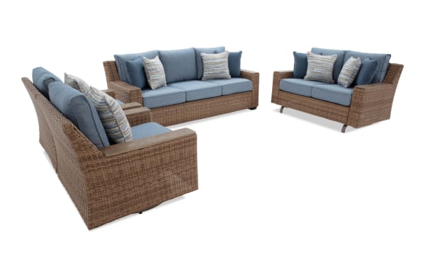 Outdoor wicker patio furniture set with blue cushions, including a three-seater sofa, loveseat, and armchair, featuring striped accent pillows.