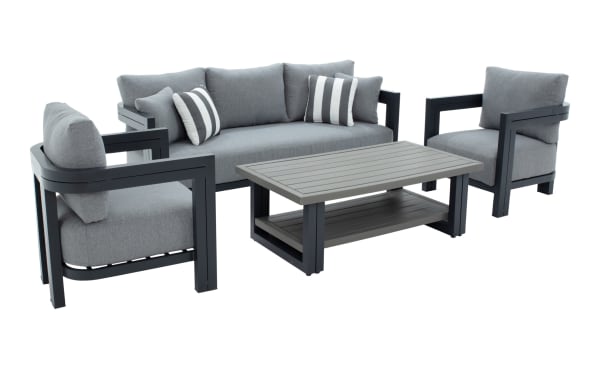 Modern outdoor patio furniture set with dark gray aluminum frame, light gray cushions, two striped accent pillows, and a matching slatted coffee table.