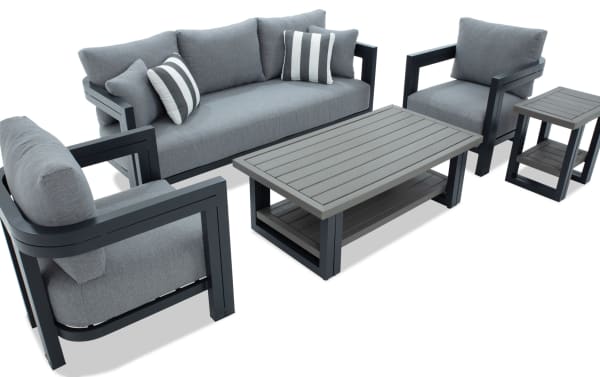 Modern outdoor patio furniture set with gray cushioned sofa, two armchairs, matching coffee table, and side table featuring black metal frames and slatted surfaces.