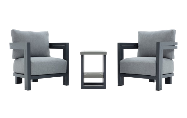 Modern outdoor patio set with two gray cushioned armchairs and a matching side table, featuring dark metal frames and plush fabric upholstery.