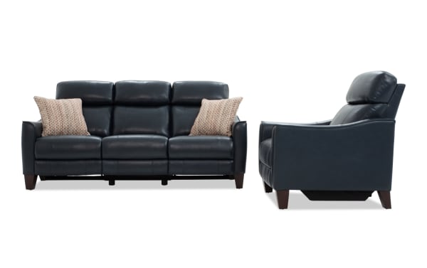 Black leather reclining sofa and matching armchair set with wooden legs and patterned accent pillows, modern living room furniture.