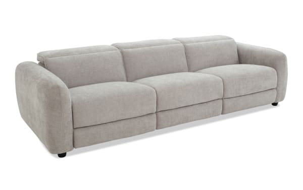 Modern three-seater sofa upholstered in light gray fabric with rounded arms, plush cushions, and low black legs, ideal for contemporary living rooms.