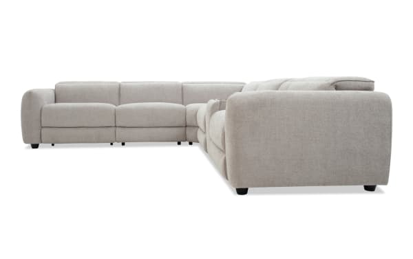 Large L-shaped sectional sofa upholstered in light beige fabric with plush cushions, rounded armrests, and low black legs, ideal for modern living rooms.
