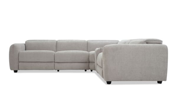 Modern L-shaped sectional sofa in light gray fabric upholstery with plush cushions, rounded armrests, and black wooden legs, ideal for contemporary living rooms.