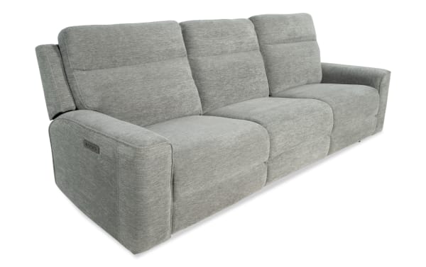 Modern three-seater reclining sofa in light gray fabric with padded armrests and adjustable headrests, featuring a side control panel.