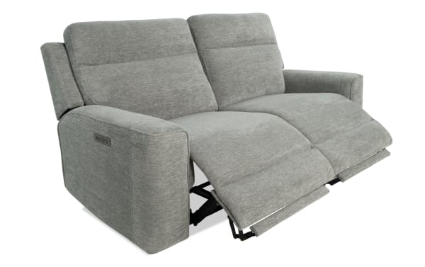 Gray fabric reclining loveseat with padded armrests and adjustable footrests, designed for comfort and relaxation.