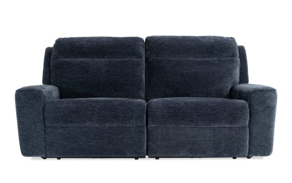 Dark gray fabric reclining loveseat sofa with plush cushions and padded armrests, designed for comfort and modern living room decor.