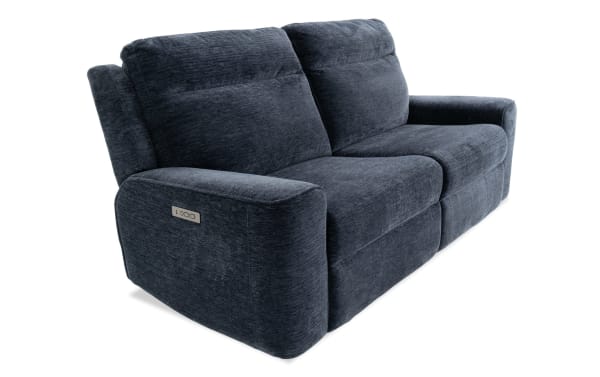 Dark gray fabric reclining loveseat with plush cushioning and padded armrests, featuring a modern design and a control panel on the side.