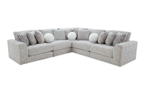 Gray L-shaped sectional sofa with plush fabric upholstery, featuring multiple textured square and round throw pillows for modern living room comfort.