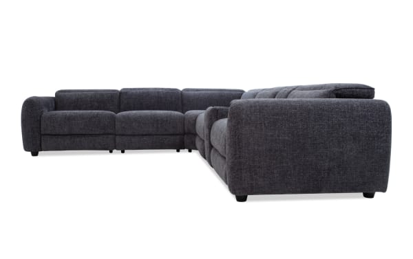 Dark gray fabric sectional sofa with plush cushions, tufted backrest, and rounded armrests, designed for modern living rooms.