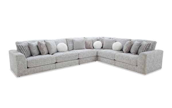 Large L-shaped sectional sofa upholstered in light gray fabric with multiple textured gray and white throw pillows, ideal for modern living rooms.